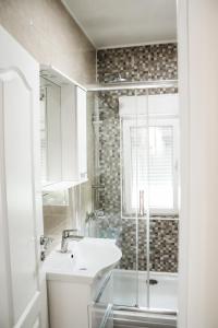 y baño blanco con lavabo y ducha. en Sunny House, en Čapljina