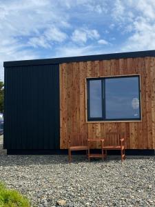 a wooden building with a bench and a window at Unique luxurious cabin on sea view working croft in Garrabost