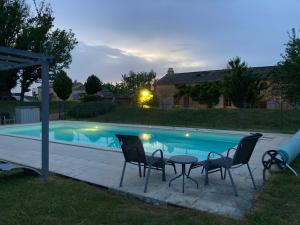 a table and chairs next to a swimming pool at Lueurs de Gorce in Barjou