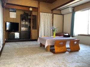 salon ze stołem, krzesłami i telewizorem w obiekcie 伊豆海の家（Izu Seaside Villa） w mieście Higashiizu