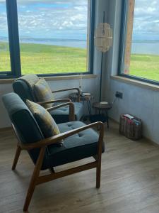 a living room with a chair and a large window at Unique luxurious cabin on sea view working croft in Garrabost