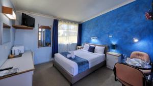 a bedroom with a large bed and a blue wall at BUSHMANS RETREAT MOTOR INN in Gundagai