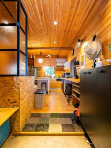 びわ湖ハイドアウト في Takashima: مطبخ كبير بسقوف خشبية وثلاجة