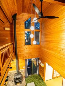 びわ湖ハイドアウト في Takashima: كابينة خشب بها موقد ومروحة سقف