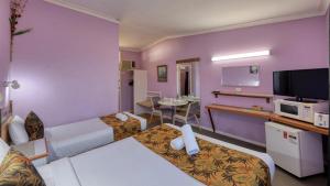 a hotel room with a bedroom with purple walls at BUSHMANS RETREAT MOTOR INN in Gundagai