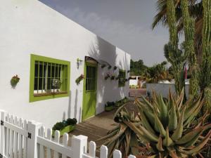 una casa blanca con una puerta verde y cactus en Cactus en Sevilla