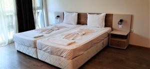 a large bed with white sheets and towels on it at Алюр студио Приморско - Studio Allure Primorsko in Primorsko +11 photos