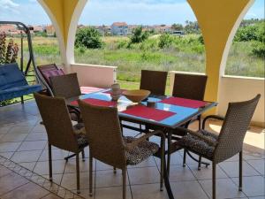 - une table et des chaises sur une terrasse avec vue dans l'établissement Apartments Lug 2, new and comfortable with pool, à Privlaka