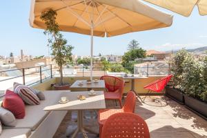 een patio met een tafel en stoelen en een parasol bij C Suites in Rethimnon