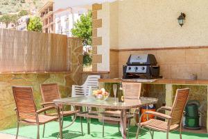 una mesa y sillas en un patio con parrilla en Casa La Loma de Arenas, en Arenas