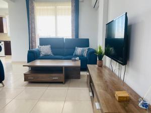 a living room with a blue couch and a tv at Apollo 2-BR Apt in Larnaca in Larnaca