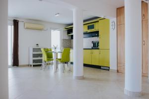 cocina con armarios amarillos, mesa y sillas en Villa Vinko, en Trogir