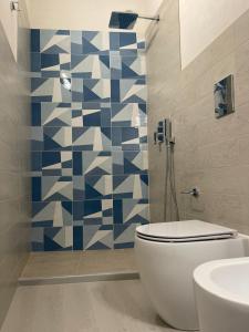 uma casa de banho com WC e azulejos azuis e brancos. em Calafato Guest House em Favignana