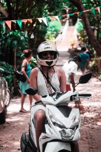 a woman riding a motor scooter down a street at Oasis Balili Heritage Lodge in Tagbilaran City