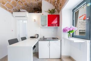 a kitchen with white cabinets and pink flowers in a vase at Unique Cavtat Center Apartment in Cavtat