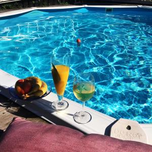 two glasses of wine and fruit on a tray next to a swimming pool at Sval källarlägenhet på natur- och havsnära Stensö in Kalmar