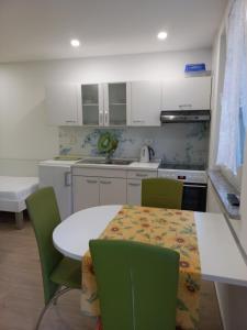 a kitchen with a white table and green chairs at Apartments Karmen in Portorož