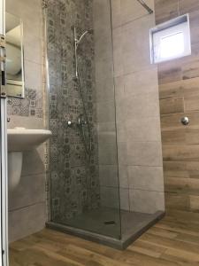 a shower with a glass door next to a sink at Вила TIMeS in Kiten