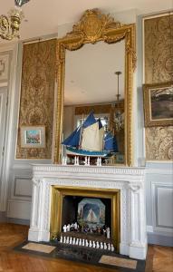 a fireplace with a pirate ship in a mirror at Appartement de charme dans château du XIXème in Lentilly