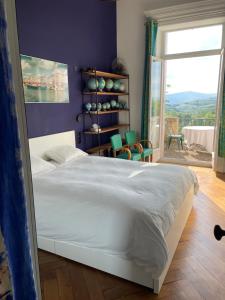 ein Schlafzimmer mit einem weißen Bett und einem großen Fenster in der Unterkunft Appartement de charme dans château du XIXème in Lentilly