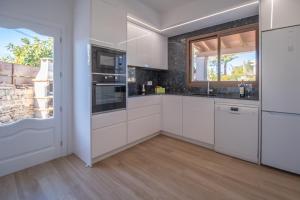 アルクーディアにあるVilla PARAISO Alcudiaの白いキャビネットと大きな窓付きのキッチン