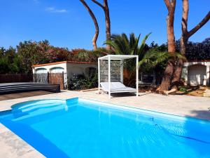 - une piscine bleue avec une chaise blanche et une balançoire dans l'établissement Domaine des Pins, à Saint-Estève