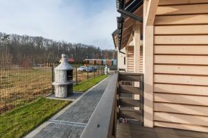 a wooden building with a walkway next to a fence at Ośrodek Wypoczynkowy DAKAR in Rewal