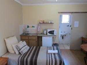 um pequeno quarto com uma cama e uma cozinha em Bedrock Guesthouse em Bloemfontein
