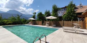 a swimming pool with chairs and umbrellas next to a house at Mittelbergerhof Ferienwohnungen in Vilpiano