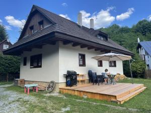 ein Haus mit einer Terrasse mit einem Tisch und einem Sonnenschirm in der Unterkunft Chata za potokom in Terchová
