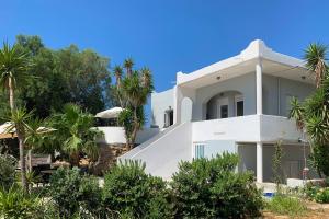 una casa blanca con palmeras delante en Villa Memories, en Palaiochóra