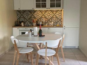 a kitchen with a table with chairs and a bottle of wine at LUČI jūras apartamenti 2 in Roja