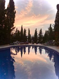 a large swimming pool with a sunset in the background at Bakit House - Casa rural con piscina in Águilas