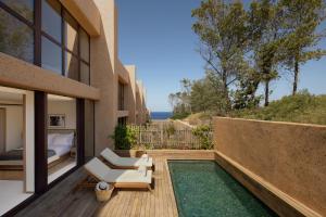 a room with a balcony with a bed and a chair at Six Senses Ibiza in Portinatx