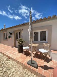 eine Terrasse mit einem Sonnenschirm, 2 Stühlen und einem Tisch in der Unterkunft Vila Lobo Algarve in Faro