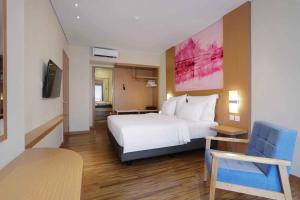 a hotel room with a white bed and a chair at favehotel Nagoya - Batam in Batam Center