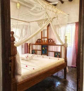 1 dormitorio con cama con dosel y sábanas blancas en MARS A.K. VILLAS, en Jambiani