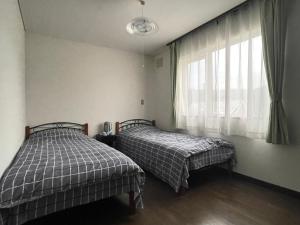 two beds in a room with a window at 京樽3号 1棟貸切 一軒家 3-Bedrooms Duplex Private Villa KYOTARU3 in Otaru
