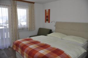 Schlafzimmer mit einem Bett, einem Stuhl und Fenstern in der Unterkunft Haus Kocher in Haus im Ennstal