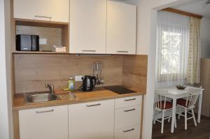 eine Küche mit weißen Schränken, einer Spüle und einem Tisch in der Unterkunft Haus Kocher in Haus im Ennstal