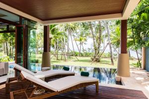 an outdoor patio with two chairs and a pool at Amatapura Beachfront Villa 14, SHA Certified in Ao Nam Mao