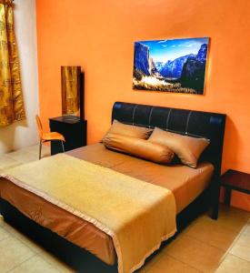 ein Schlafzimmer mit einem Bett mit einer orangefarbenen Wand in der Unterkunft StayLena Klebang Melaka Homestay - Musliem Unit in Malakka