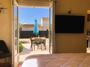 a bedroom with a door open to a patio with a table and an umbrella at Castel Mireio Gîtes in Cairanne