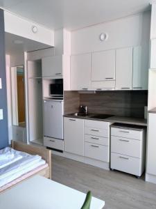 Biała kuchnia z białymi szafkami i zlewem w obiekcie Harju Apartments w mieście Jyväskylä