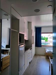 a kitchen with white cabinets and a large window at Harju Apartments in Jyväskylä