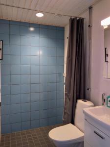 a blue tiled bathroom with a toilet and a sink at Harju Apartments in Jyväskylä