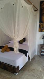 a bedroom with two beds with white curtains at Elephant House and Bungalows Gili Air in Gili Air