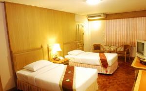 a hotel room with two beds and a television at Silom Village Inn in Bangkok