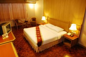 a hotel room with a large bed and a television at Silom Village Inn in Bangkok