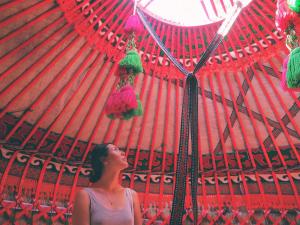 une femme se tient sous un parapluie rouge dans l'établissement SilkRoad Guesthouse, à Bishkek